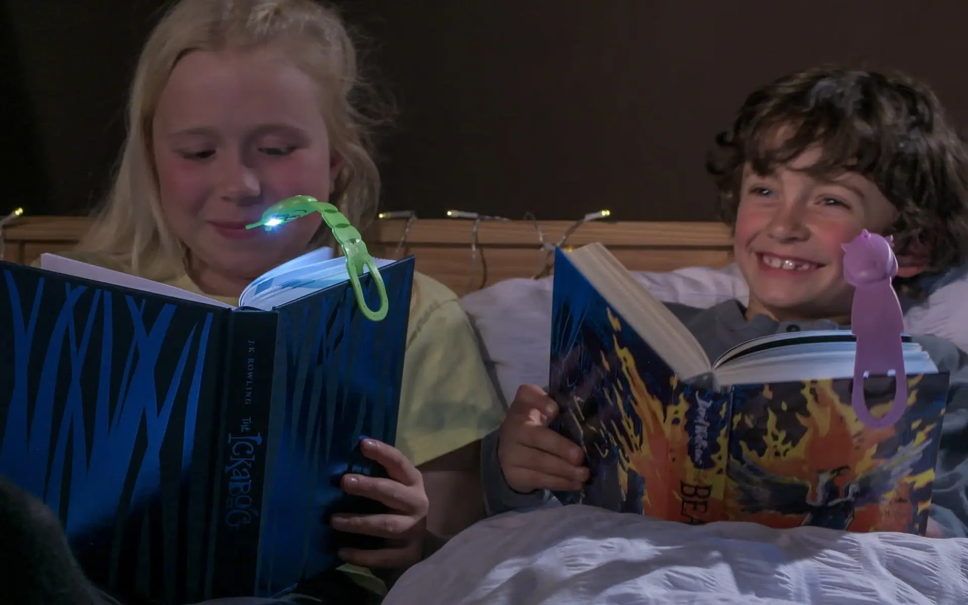 Two children reading in the dark with Flexilight clip-on book lights